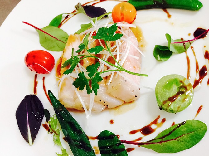 写真:魚の白身の周りに鮮やかな野菜が配置された美しい料理